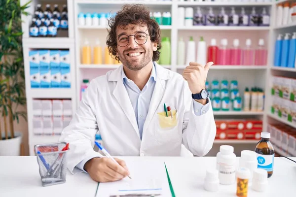 Jovem Hispânico Trabalhando Farmácia Drogaria Apontando Para Costas Com Mão — Fotografia de Stock