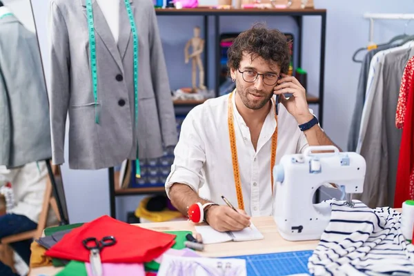 Jonge Spaanse Man Kleermaker Praten Smartphone Schrijven Notebook Kledingfabriek — Stockfoto