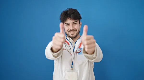 Fiatal Spanyol Férfi Orvos Csinál Hüvelykujj Fel Izolált Kék Háttér — Stock Fotó