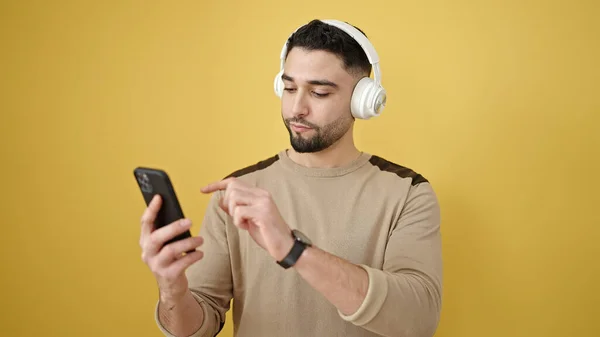 Jovem Árabe Homem Usando Fones Ouvido Usando Smartphone Sobre Fundo — Fotografia de Stock