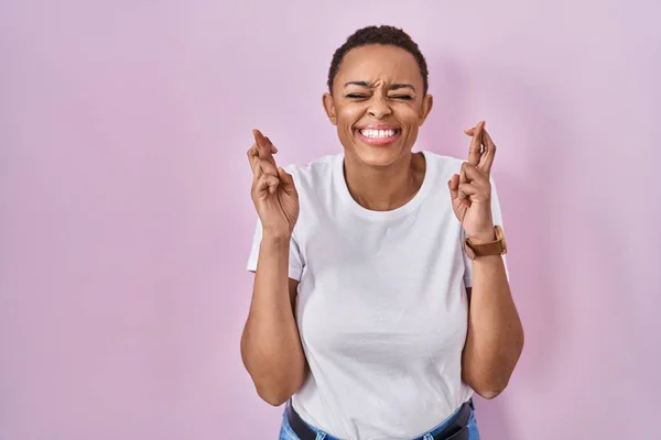 Beautiful African American Woman Standing Pink Background Gesturing Finger Crossed — Stock Photo, Image