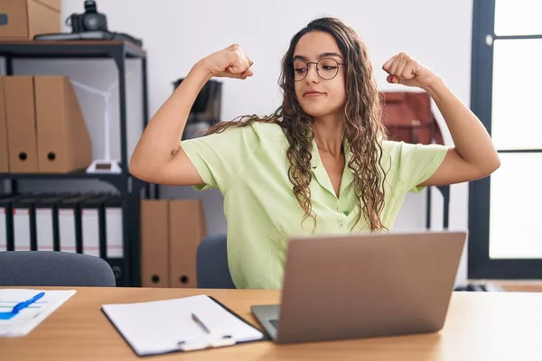 在办公室工作的年轻惊慌失措的女人戴着眼镜 露出胳膊肌肉 笑得很自豪 健身概念 — 图库照片