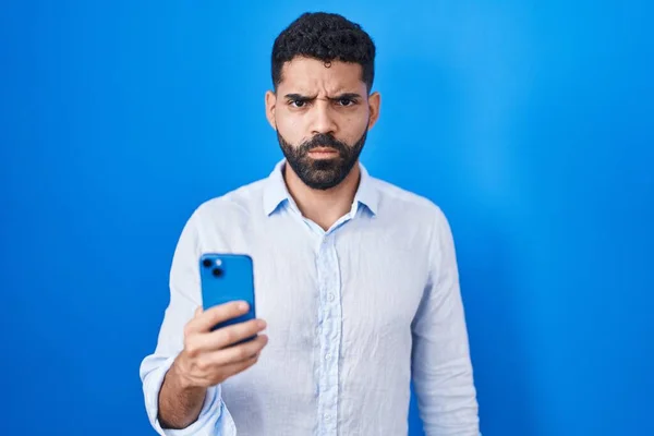 Hispanic Man Beard Using Smartphone Typing Message Skeptic Nervous Frowning — Fotografia de Stock