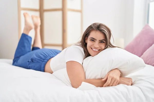 年轻女人抱着枕头躺在卧室的床上 — 图库照片