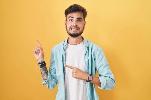 Young Hispanic Man Tattoos Standing Yellow Background Pointing Aside Worried — Fotografia de Stock