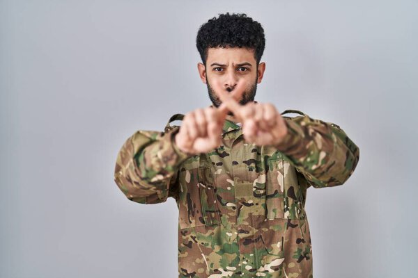 Arab man wearing camouflage army uniform rejection expression crossing fingers doing negative sign 