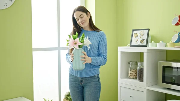 stock image Young caucasian woman holding plant standing at dinning room