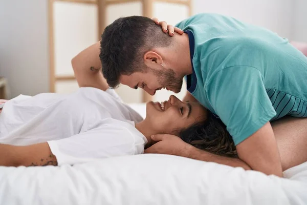 若いですヒスパニックカップル抱擁お互いにベッドの上に寝そべって — ストック写真