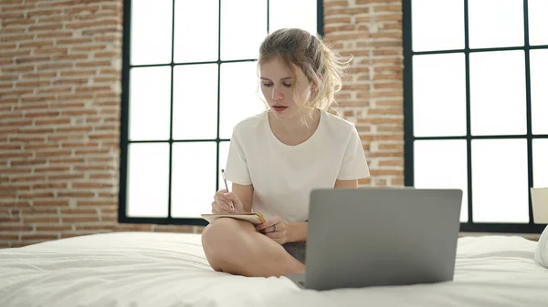 Young Blonde Woman Using Laptop Writing Notebook Sitting Bed Bedroom — 스톡 사진
