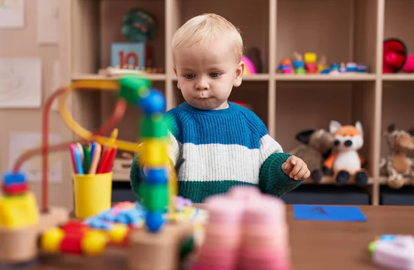 愛らしい白人の男の子遊びますおもちゃとともにテーブルの上に座って幼稚園 — ストック写真