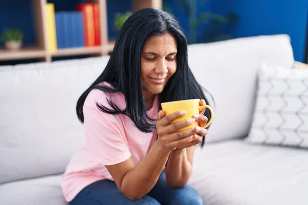 Middle Age Hispanic Woman Drinking Coffee Sitting Sofa Home — Fotografia de Stock