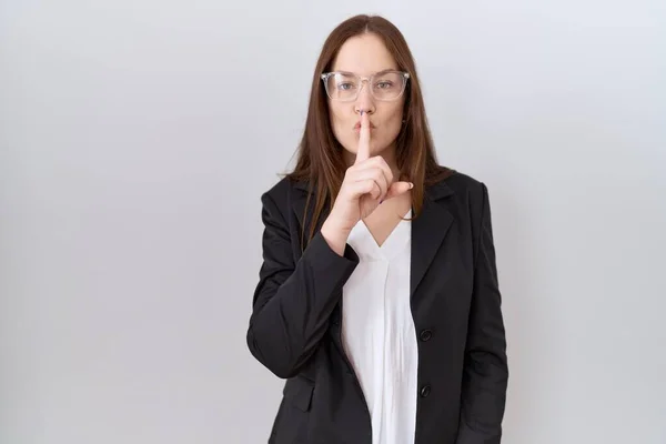 ビジネスジャケットとメガネを身に着けている美しいブルネットの女性は唇に指で静かになるように求めている 沈黙と秘密の概念 — ストック写真