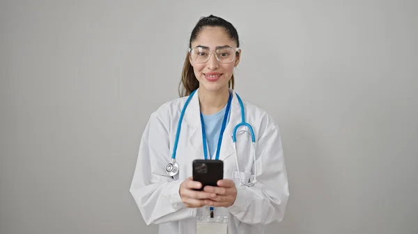 年轻美丽的惊慌失措的女医生用智能手机在孤独的白色背景下微笑 — 图库照片