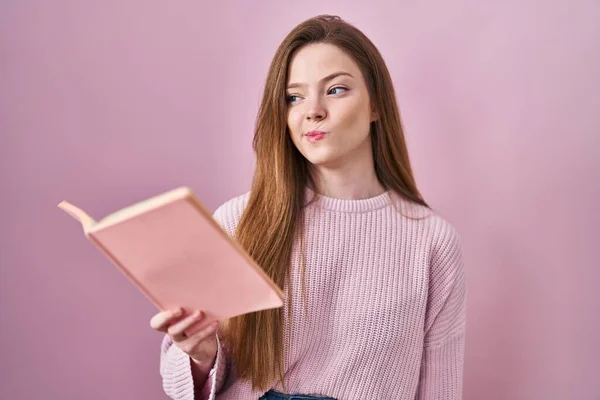 Νεαρή Καυκάσια Γυναίκα Διαβάζει Ένα Βιβλίο Πάνω Από Ροζ Φόντο — Φωτογραφία Αρχείου