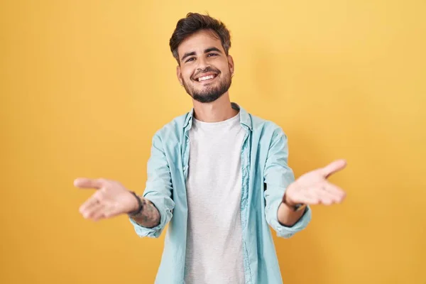 Young Hispanic Man Tattoos Standing Yellow Background Smiling Cheerful Offering — стоковое фото