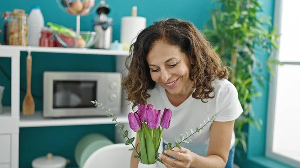 Middle Age Hispanic Woman Smelling Flowers Vase Putting Table Dinning — Stock Photo, Image