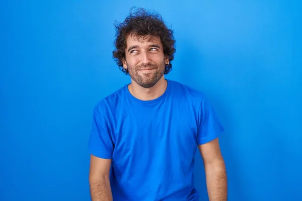 Ισπανόφωνος Νεαρός Άνδρας Στέκεται Πάνω Από Μπλε Φόντο Χαμογελώντας Κοιτάζοντας — Φωτογραφία Αρχείου