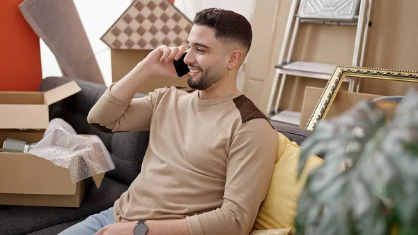 Young arab man smiling confident talking on smartphone at new home