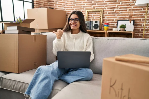 stock image Young hispanic woman sitting on the sofa at new home using laptop looking at the camera smiling with open arms for hug. cheerful expression embracing happiness. 