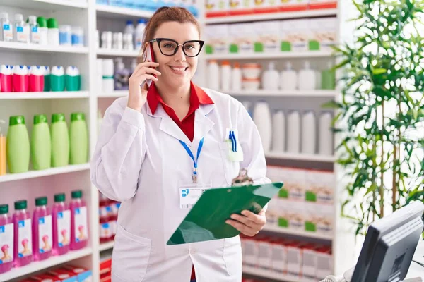 Young Beautiful Size Woman Pharmacist Talking Smartphone Reading Document Pharmacy — Zdjęcie stockowe