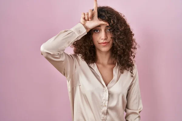 Pembe Arka Planda Duran Kıvırcık Saçlı Spanyol Kadın Alnında Parmakları — Stok fotoğraf