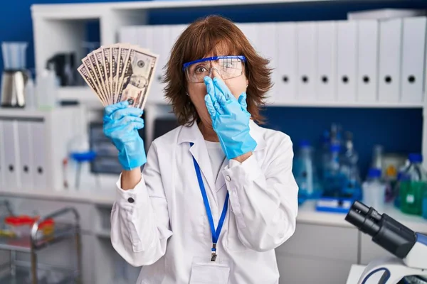 Женщина Средних Лет Работающая Научной Лаборатории Держит Деньги Прикрывая Рот — стоковое фото