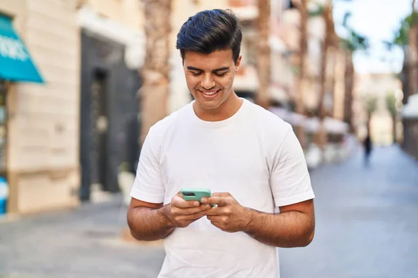 在街上用智能手机自信地微笑着的年轻人 — 图库照片