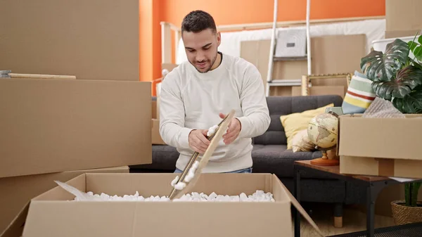 Young Hispanic Man Unpacking Cardboard Box New Home — Stockfoto