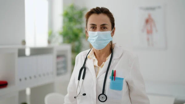 中年妇女穿着医生制服 戴着医疗面罩在诊所 — 图库照片