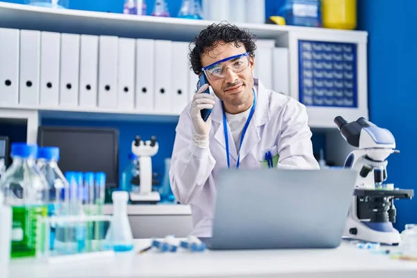 Young Hispanic Man Scientist Using Laptop Talking Smartphone Laboratory — Stock Photo, Image