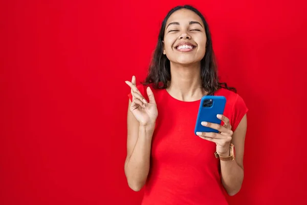Nuori Brasilialainen Nainen Joka Käyttää Älypuhelinta Punaisen Taustan Eleenä Sormi — kuvapankkivalokuva