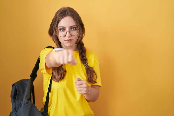 年轻的高加索女人背着学生背包 背着黄色背景的拳头打斗 挑衅和愤怒的攻击 威胁和暴力 — 图库照片