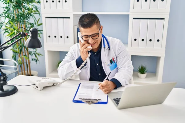 Ung Latinamerikansk Man Läkare Talar Telefon Skriva Dokument Kliniken — Stockfoto