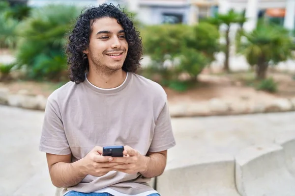 Młody Latynos Człowiek Pomocą Smartfona Siedzi Ławce Parku — Zdjęcie stockowe