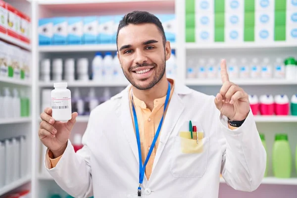 Jovem Hispânico Trabalhando Farmácia Farmácia Segurando Pílulas Sorrindo Com Uma — Fotografia de Stock