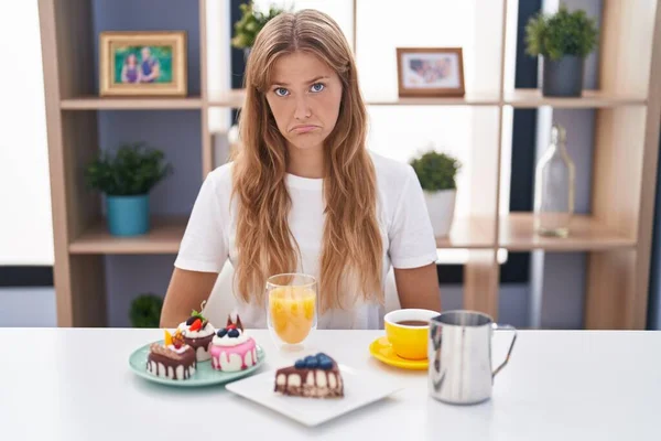 若い白人女性は朝食のためにペストリーを食べて落ち込んで苦痛を心配し 怒りと恐怖を泣いています 悲しい表情 — ストック写真