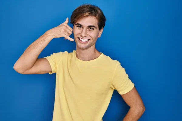 Jeune Homme Debout Sur Fond Bleu Souriant Faire Geste Téléphone — Photo