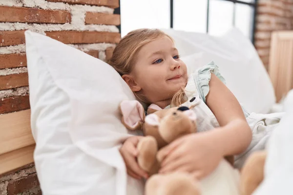 Liebenswert Blond Mädchen Holding Puppe Liegend Auf Bett Schlafzimmer — Stockfoto