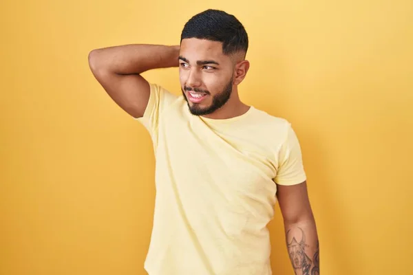 Young Hispanic Man Standing Yellow Background Smiling Confident Touching Hair — Stock fotografie