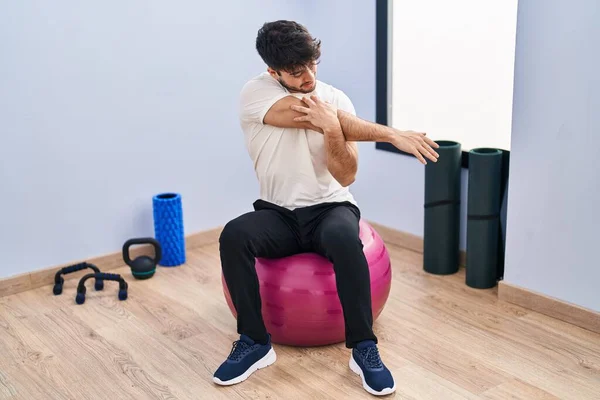 Young Hispanic Man Sitting Fit Ball Stretching Sport Center — стоковое фото
