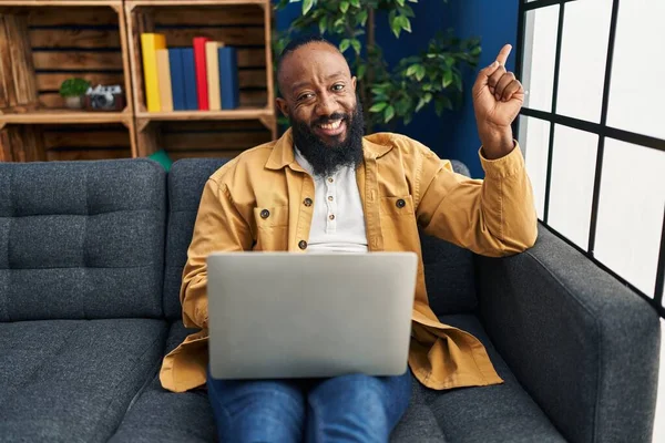 Африканский Американец Сидящий Дома Ноутбуком Диване Улыбающийся Счастливый Указывающий Рукой — стоковое фото