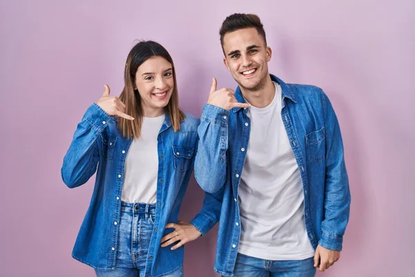 Young Hispanic Couple Standing Pink Background Smiling Doing Phone Gesture — 图库照片