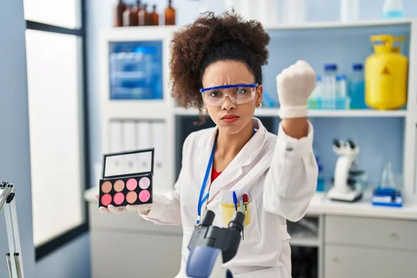 Young african american woman working at scientist laboratory doing make up annoyed and frustrated shouting with anger, yelling crazy with anger and hand raised