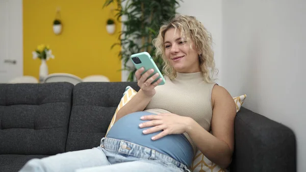 Молодая Беременная Женщина Помощью Смартфона Трогает Живот Дома — стоковое фото