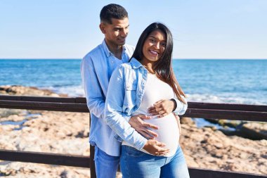 Genç, Latin bir çift bebek bekliyor. Birbirlerine sarılıyorlar.