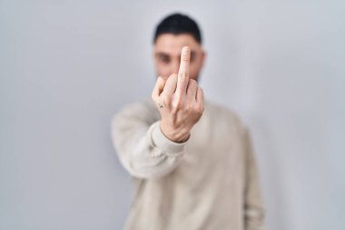 Young handsome man standing over isolated background showing middle finger, impolite and rude fuck off expression 