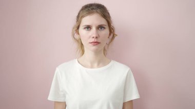 İzole edilmiş pembe arka planda rahat yüzü olan genç sarışın kadın.