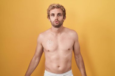 Beyaz adam üstsüz, güneş kremi sürmüş kameraya bakıyor. Havada öpücük yolluyor. Sevimli ve seksi. aşk ifadesi. 