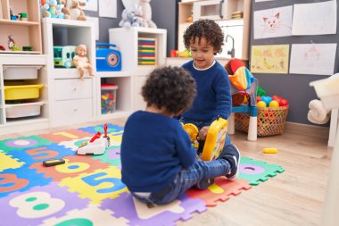 Sevimli Afro-Amerikan çocukları yerde oturup anaokulunda aletlerle oynuyorlar.