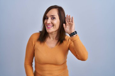 Orta yaşlı esmer kadın turuncu kazak giymiş, kulağı kulağında bir dedikodu ya da dedikoduyu dinliyor. Sağırlık kavramı. 